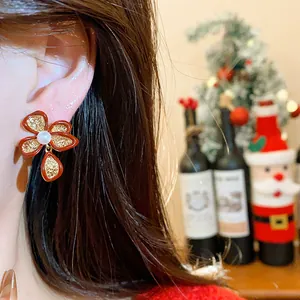 Detail shot of a red and gold flower stud earring worn by a model