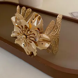 Detail shot of elegant gold flower metal cuff bracelet with textured open design.