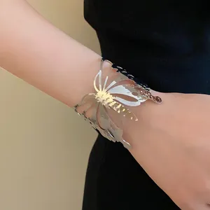 Close-up view of a silver-toned metal butterfly open cuff bracelet worn on a model wrist