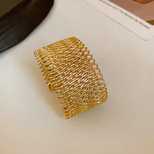 Close-up of a stylish gold-tone open cuff bracelet with intricate woven mesh metal design