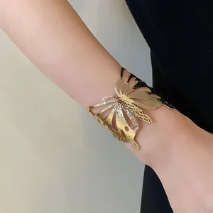 Close-up detail of an elegant gold butterfly cuff bracelet with hammered metal texture.
