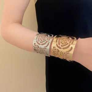 Detailed view of gold and silver metallic wide cuff bracelets with hollowed-out rose patterns