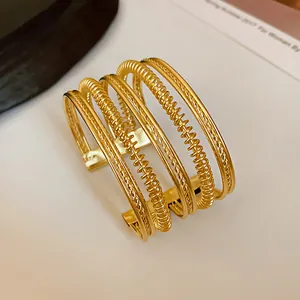 Detailed view of a minimalist gold multi-strand open cuff bracelet with textured design.