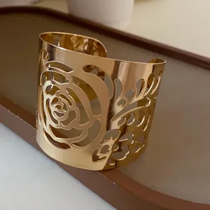 Close-up detail shot of the intricate hollowed rose pattern on the gold cuff bracelet.
