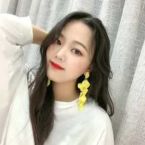 Gros plan de longues boucles d'oreilles à pompons de pétales jaunes pour un look élégant.