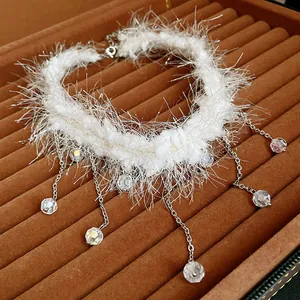 Gros plan détaillé d'un collier ras du cou en peluche blanche avec glands en cristal suspendus
