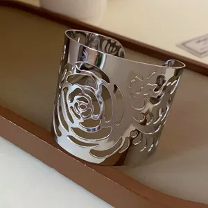 Close-up of polished silver metal open cuff bracelet with hollow-out rose design