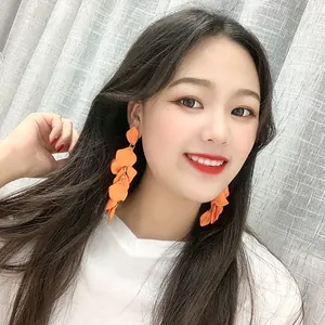 Boucles d'oreilles pendantes orange à pétales portées par une femme élégante