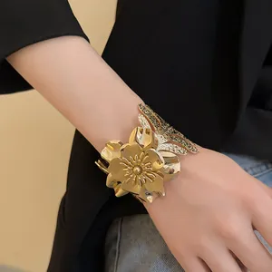 Detailed view of a luxury gold metallic flower open cuff bracelet worn on the wrist.