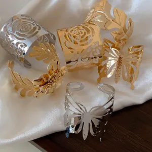 Selection of polished gold and silver cuff bracelets with intricate floral and butterfly cutouts.