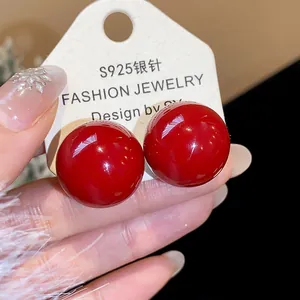 Detailansicht glänzender roter runder Ohrstecker mit S925 Silbernadeln für einen schicken Look