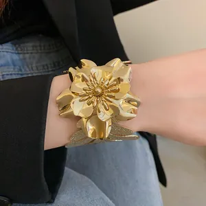 Close-up detail of a vintage gold metallic flower open cuff bracelet worn on wrist