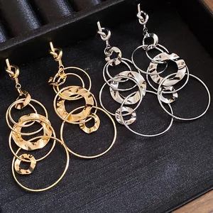 Macro detail of knotted hammered multi-layered hoop earrings in gold and silver finish