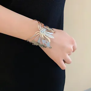 Close-up detail of a silver butterfly metallic open cuff bracelet worn on wrist.