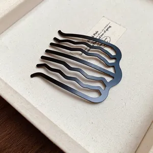 Close-up detail of a minimalist matte black wave-shaped U hair comb for bun styling.