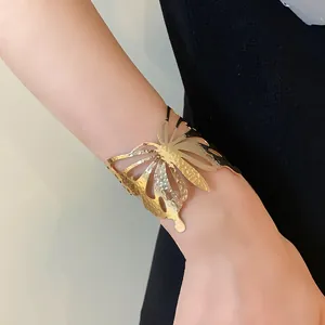 Detailed view of a gold butterfly-shaped metal cuff bracelet on a woman's wrist