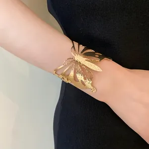 Close-up of a gold hammered butterfly cuff bracelet worn on a lady's slender wrist