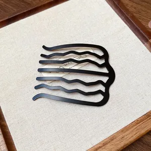 Detailed view of a matte black wavy U-shaped hair comb for elegant updos and styling.