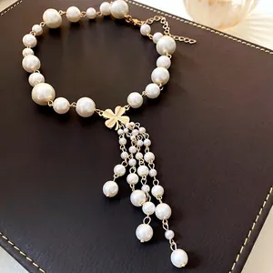 Elegante Perlenkette mit goldenem Blumenanhänger und Perlenquasten auf dunklem Leder