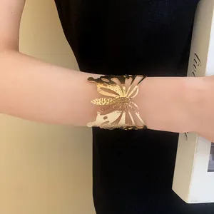 Close-up detail of a luxury hammered gold metal butterfly cuff bracelet on a model