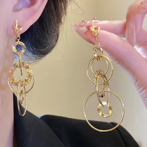 Close-up of golden knotted tassel earrings with multi-layered hollow circle design