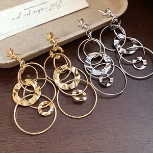 Detailed view of gold and silver multi-ring tassel earrings with hammered texture.