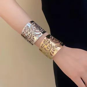Detailed view of gold and silver wide metal cuff bracelets with intricate rose cut-out patterns