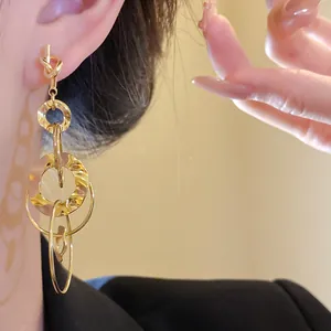 Detailed close-up of golden knotted drop earrings featuring hollowed wrinkled circles