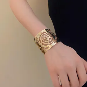 Detailed close-up of a stylish gold-plated wide cuff bracelet with hollow floral cutouts.