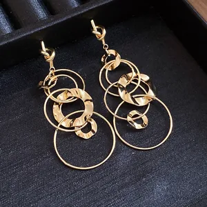 Detailed close-up of gold knotted dangle earrings with interlocking wrinkled circles