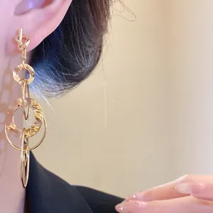 Close-up of gold knotted earrings with hammered circular texture and dangling design