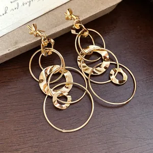 Detailed view of gold knot earrings with layered hammered circle tassels