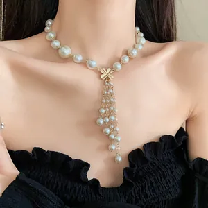 Nahaufnahme einer eleganten Perlenkette mit goldener Blume und Quasten-Details