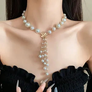 Nahaufnahme von Goldblumenquasten und Perlenanhängern an einer eleganten Halskette