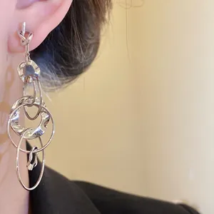 Detail view of silver knot and layered hollow circular tassel earrings worn on a model's ear