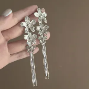 Close-up view of elegant silver floral tassel earrings featuring intricate petal details.