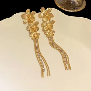 Close-up of golden flower tassel earrings with sparkling rhinestone details
