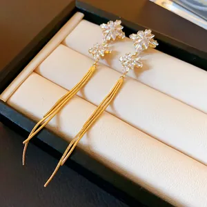 Detail view of elegant gold floral tassel earrings featuring sparkling crystal studs.