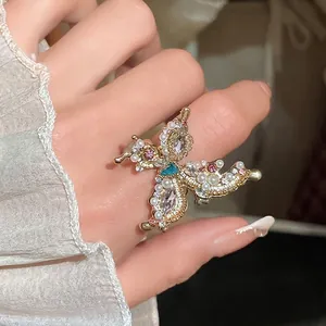 Elegant French style butterfly ring with faux pearls and sparkling rhinestones on finger