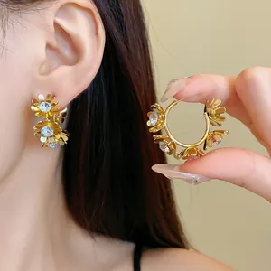 Macro view of elegant golden flower hoop earrings with crystal centers worn by model