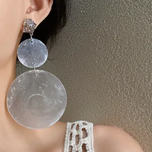 Primer plano de pendientes minimalistas de doble disco plateado puestos en la oreja