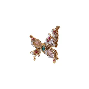 Ornate French-style butterfly ring with rhinestones and pearls on white background