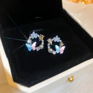 Close-up of elegant flower and butterfly earrings with crystal accents in a gift box.