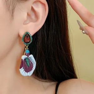 Macro view of a vintage purple floral drop earring worn on a model's ear for display
