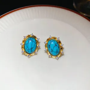 Close-up detail of elegant vintage-style gold turquoise stud earrings with a crystal halo