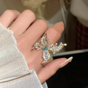 Close-up of an exquisite golden butterfly ring with pearls and rhinestones on a hand.