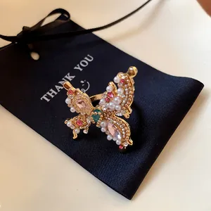 Close-up detail of a gold French-style butterfly ring with pearls and pink rhinestones