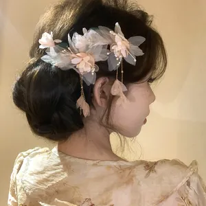Close-up of elegant pink fabric flower hair clip with pearls and long tassels
