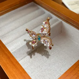 Close-up of elegant gold butterfly ring with pearls and pink crystals in jewelry box.