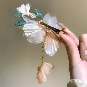 Elegant handmade fabric flower hair clip with green leaves and golden tassel detail